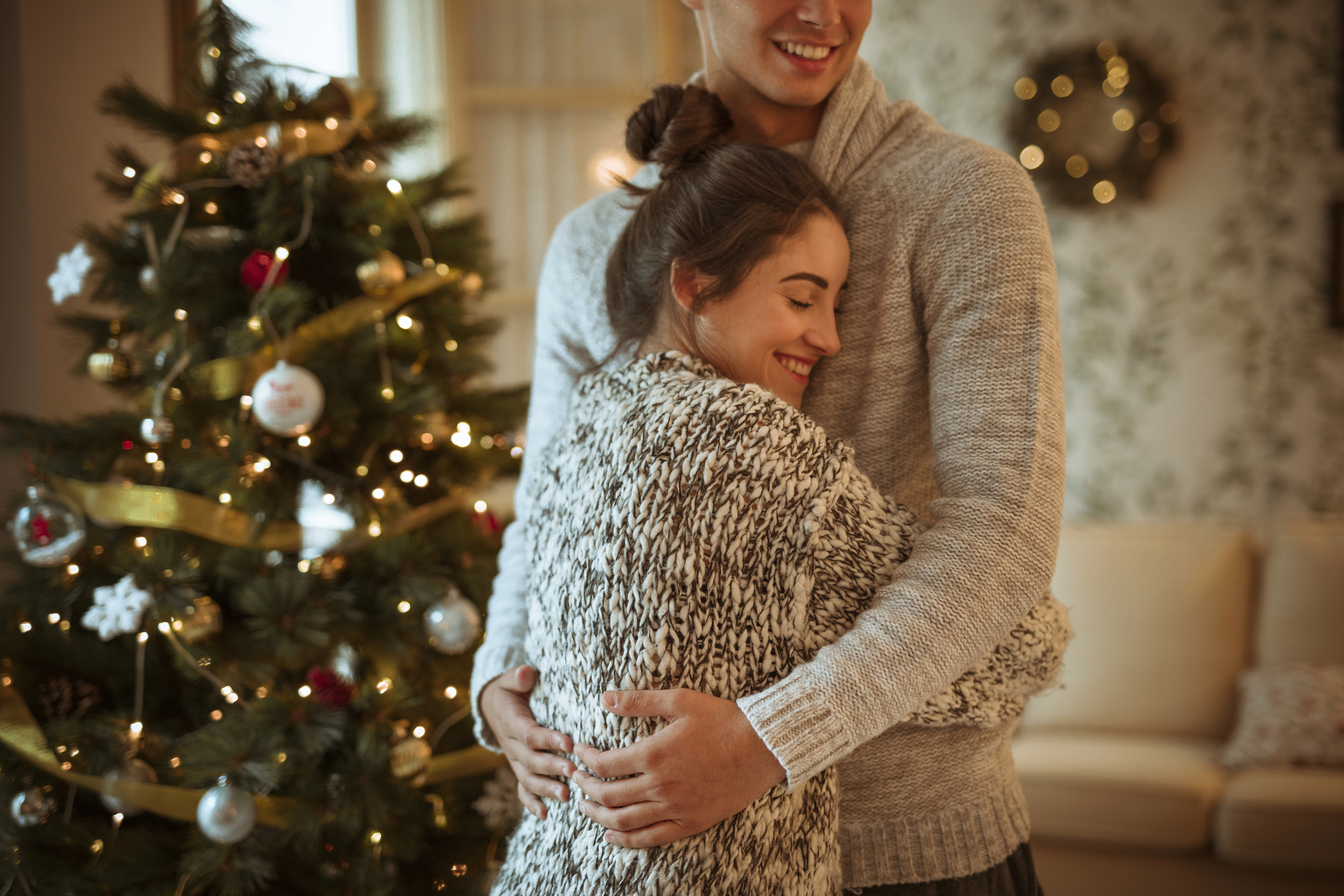 young-woman-hugging-man-near-decorated-fir-tree