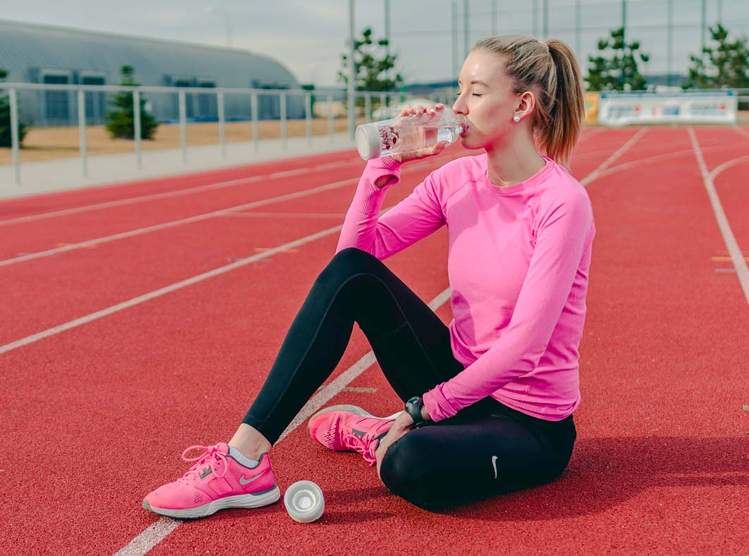 Žena na atletické dráze popíjející vodu z láhev na pití ViA VitaJuwel