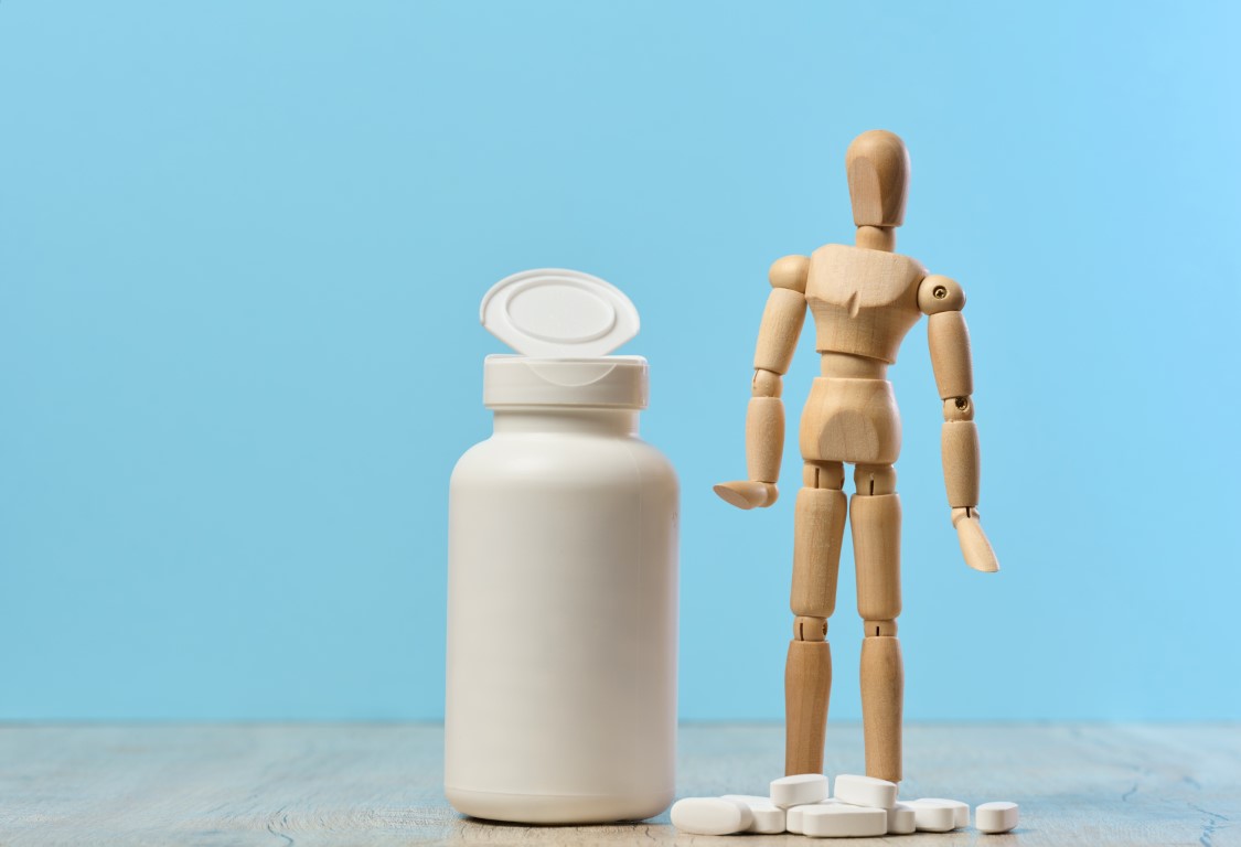 wooden-dummy-and-plastic-bottle-and-oval-white-pil-2023-12-13-00-06-39-utc