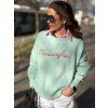 mentolový oversize sveter s nápisom na žene v mestskom outfite