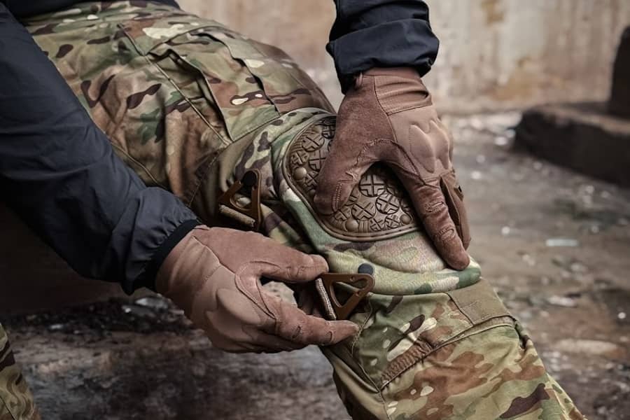Detail rukou v taktických rukavicích při zapínání kolenního chrániče ALTA®️ se systémem AltaLOK™️. Foto: Rigad