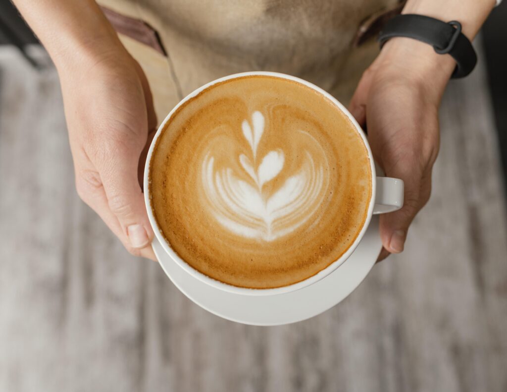 baristka drží cappuccino v ruke