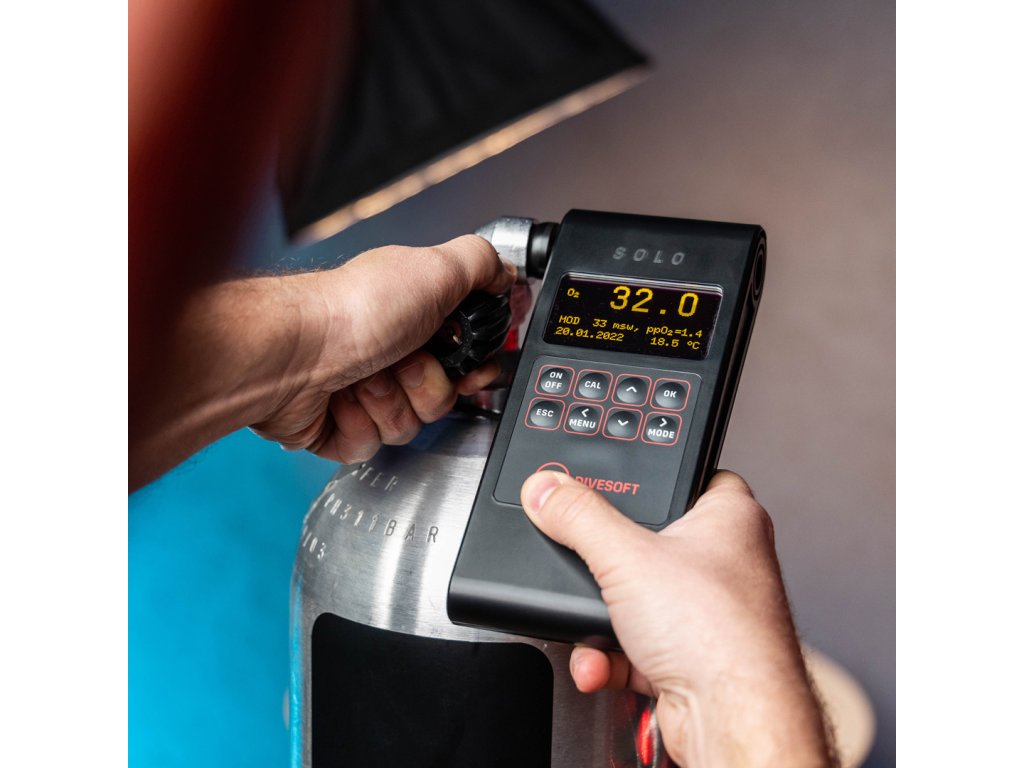 Praktická aplikácia priamo na ventil fľaše; displej zobrazuje 32,0 % O2 a príslušné limity MOD.