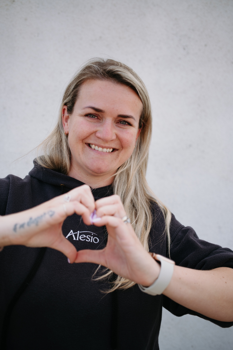 Usměvavá baristka v mikině Alesio tvoří ze svých rukou srdce jako symbol vztahu ke kávě i lidem