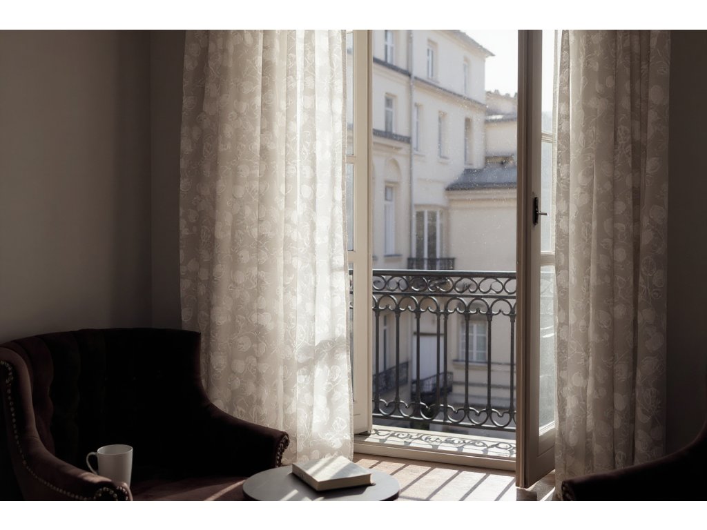 Soft, floral patterned curtains billowing gently in the breeze of a bright, sun drenched Parisian apartment, early morning light filtering through sheer