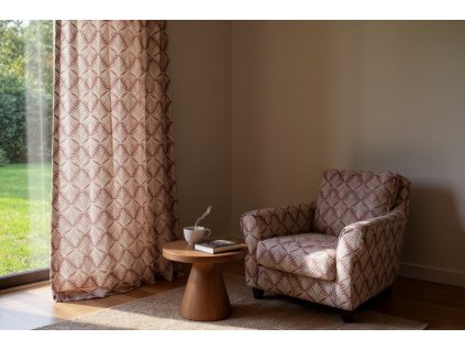 A cozy and serene reading nook bathed in soft, diffused sunlight filtering through patterned mauve and cream curtains; a plush, oversized armchair sits