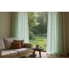 An airy, sun drenched living room featuring flowing, pale green curtains cascading from a hidden rod, framing a wide window overlooking a l