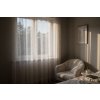 A cozy bedroom scene during golden hour, featuring sheer, silver striped curtains billowing gently in the breeze from an open window Sunlight streams through, ca
