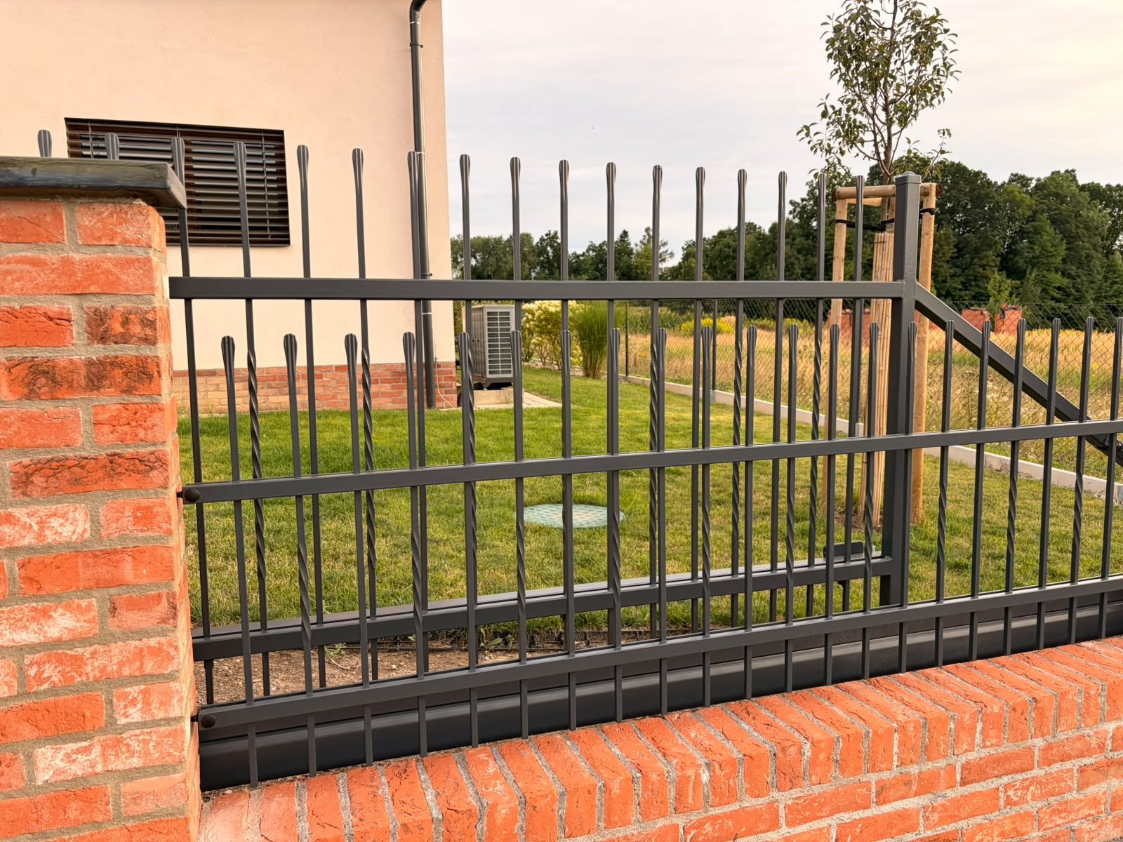 Detail plotového pole STYLE 10-23 se zdobenými svislými pruty na cihlové podezdívce