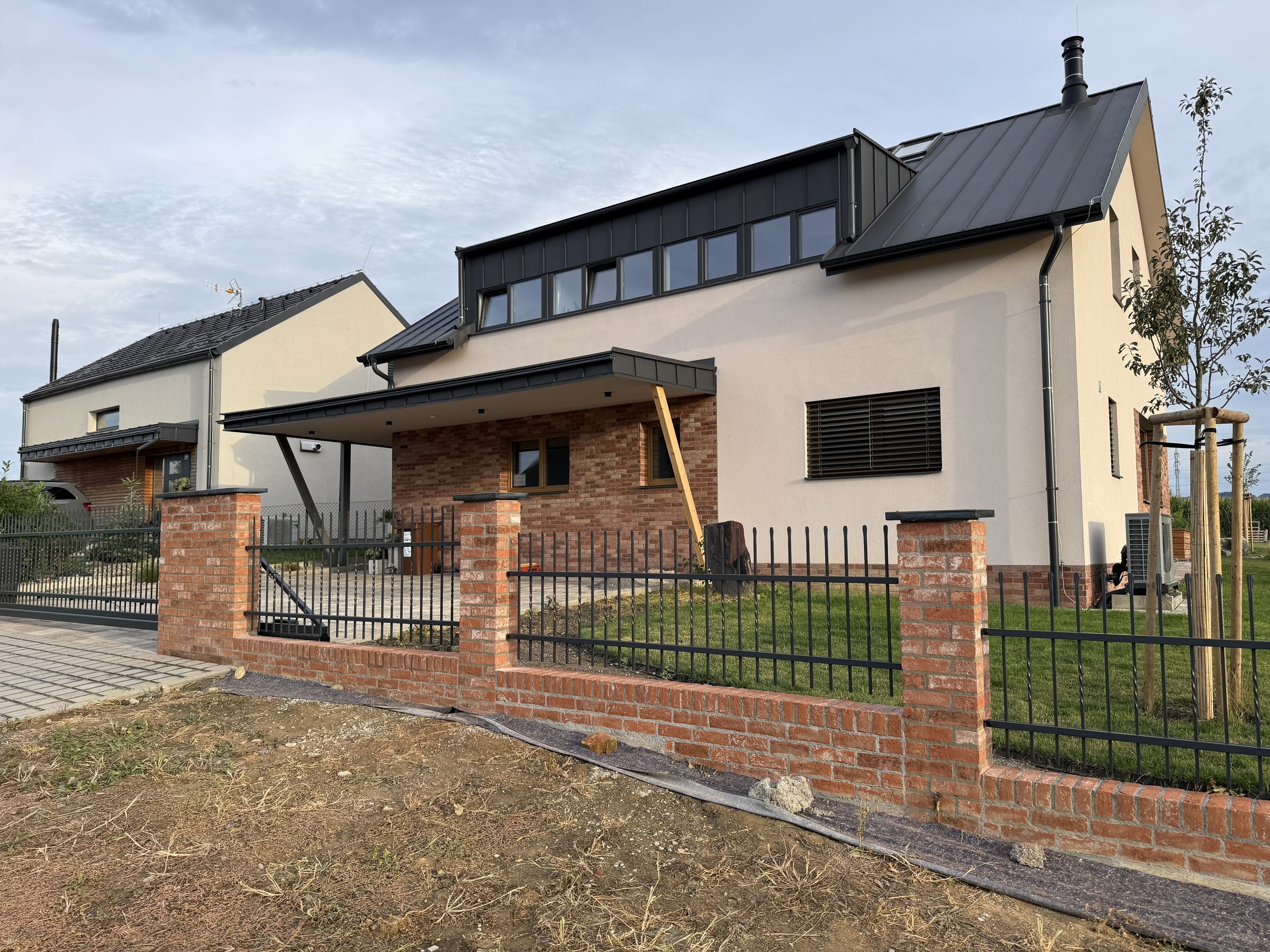 Kovaný plot STYLE 10-23 na cihlové podezdívce se sloupky, novostavba s pultovou střechou