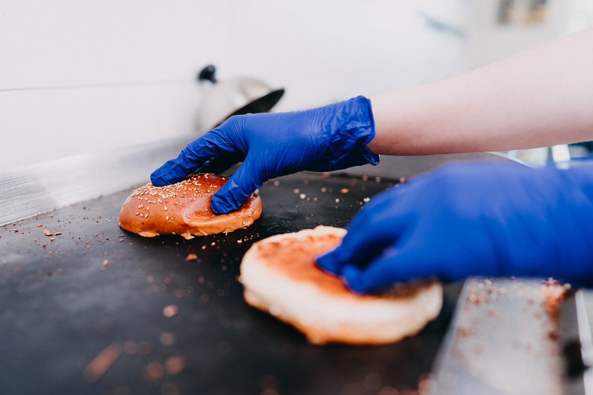 Modré rukavice Espeon při přípravě housek na grilu v bistru Ben's Burger