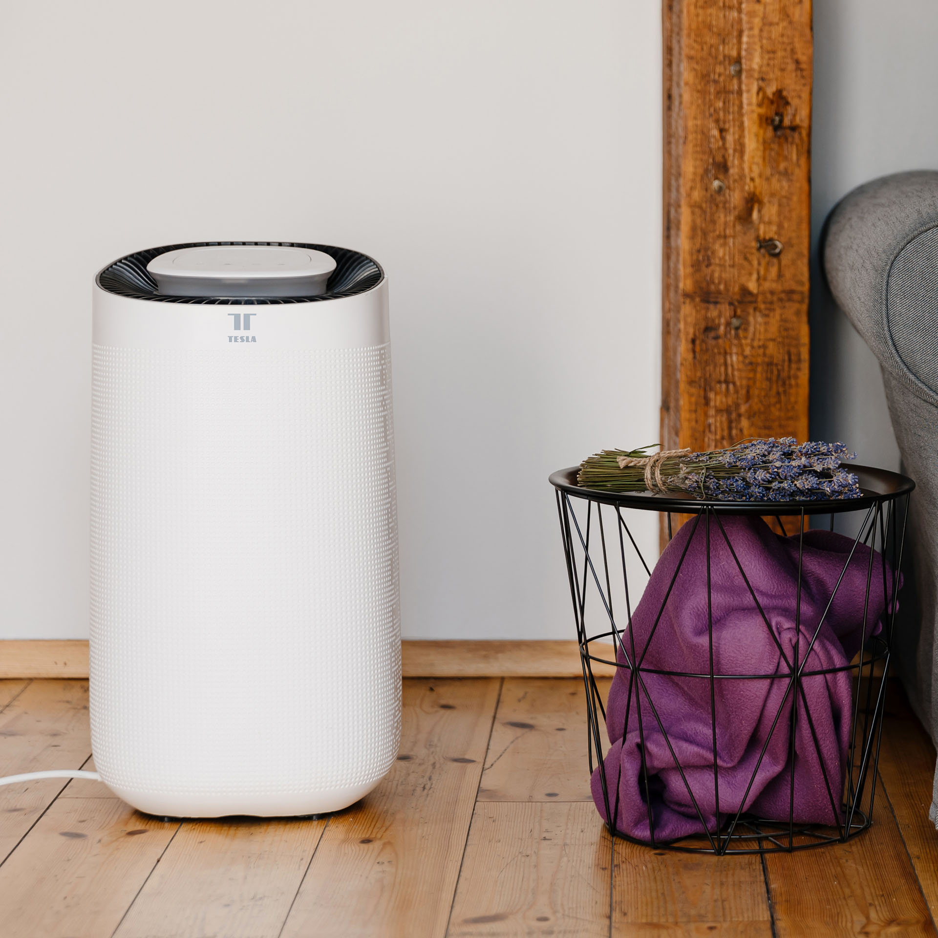 Bílý odvlhčovač Tesla Smart Air Dehumidifier XL stojící vedle stolu