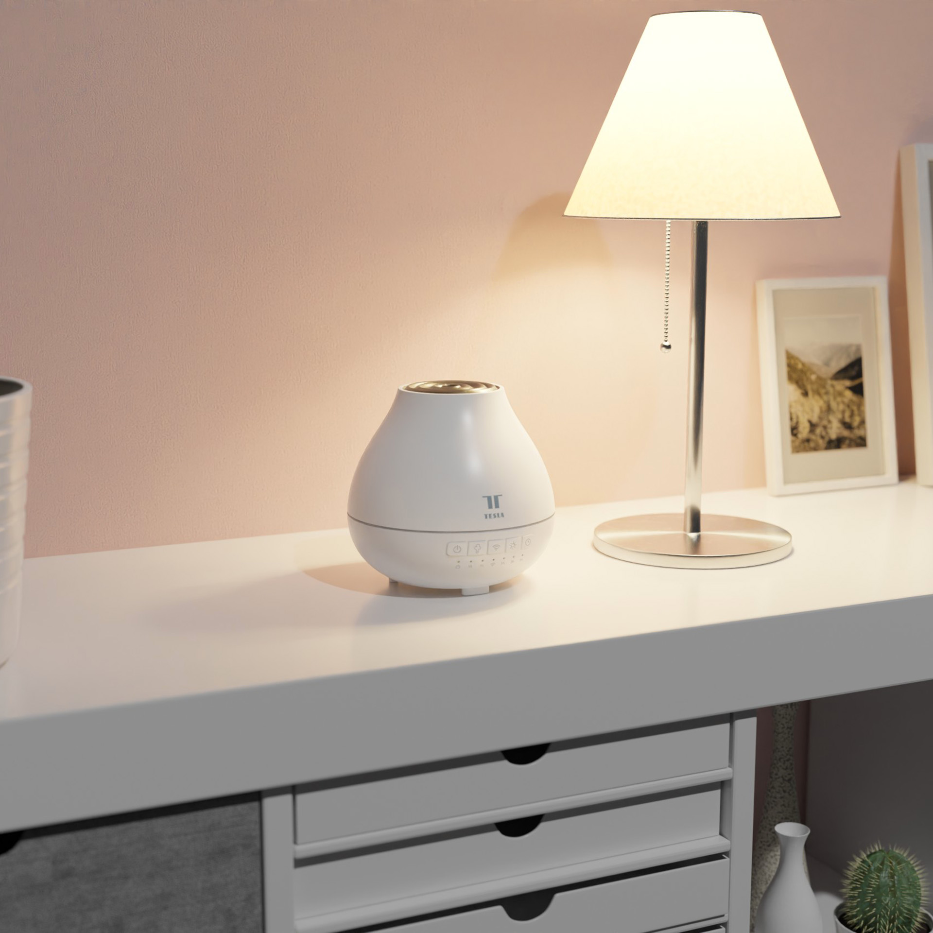 Aroma difuzér Tesla Smart Aroma Diffuser položený na komodě vedle lampičky