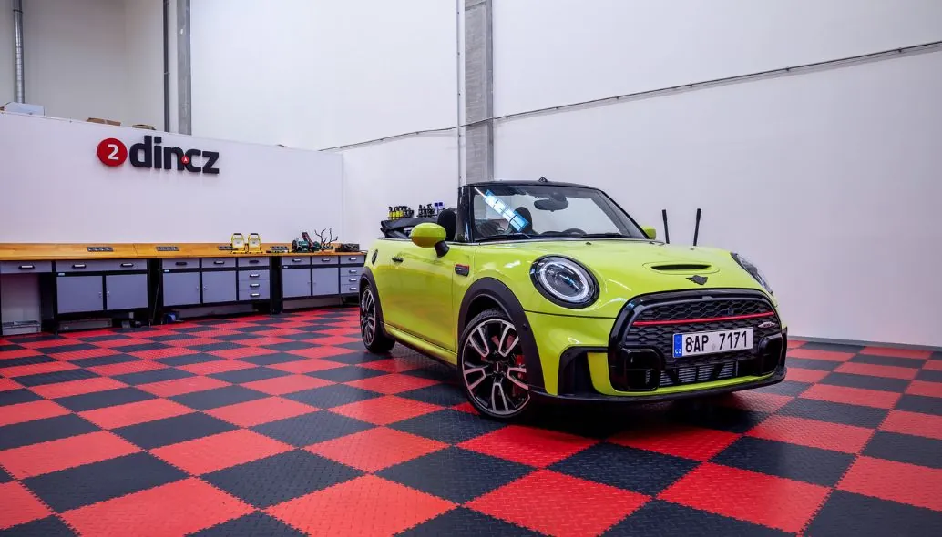 Montážní dílna 2din.cz v Letňanech – logo, pracovní stoly a auto na šachovnicové podlaze