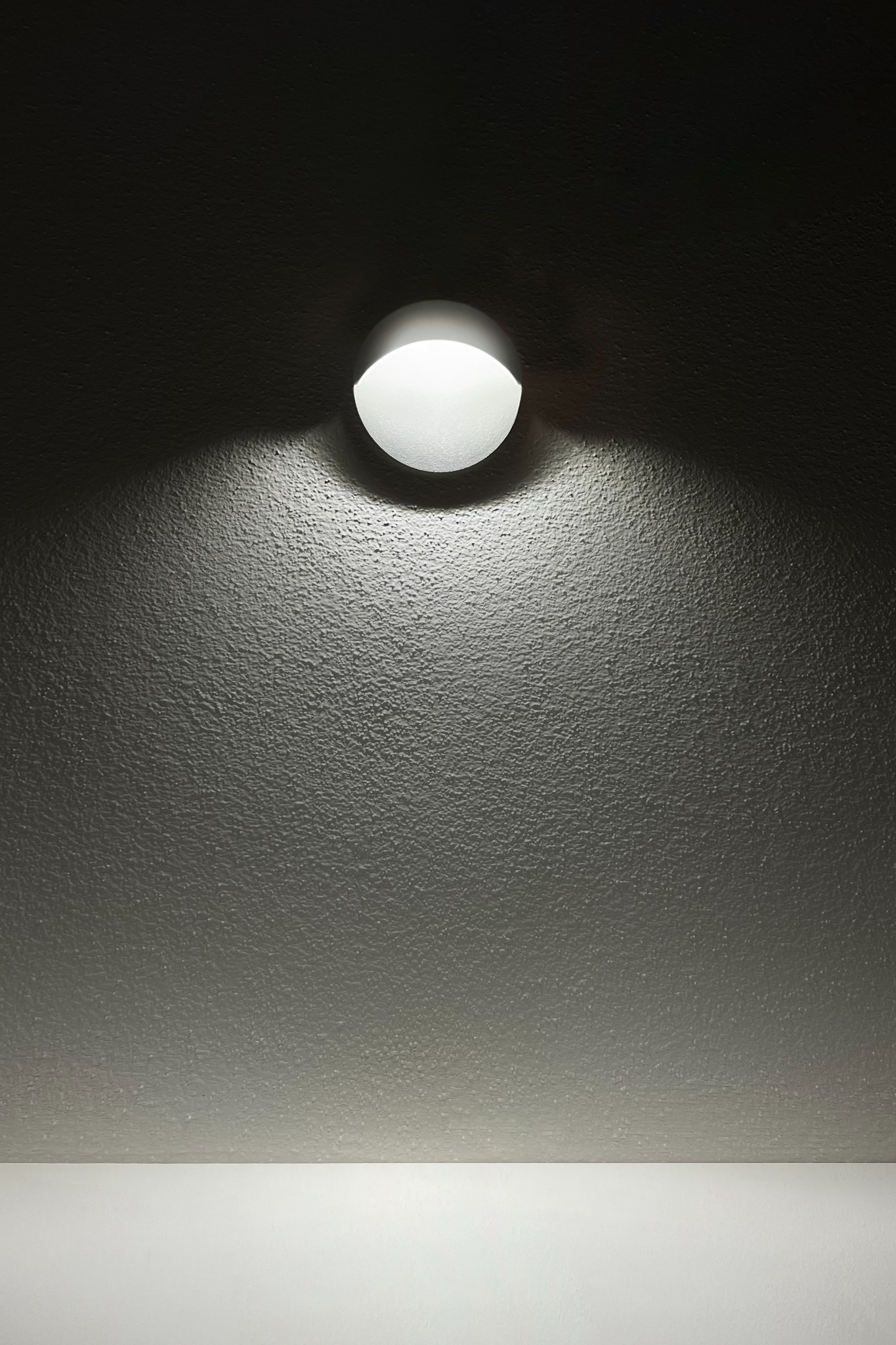 Detail svítidla s cloněným zdrojem a světlem směrovaným dolů.