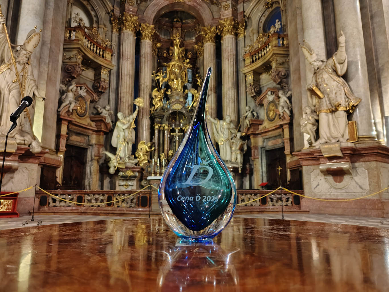 Ručně vyráběná skleněná trofej Cena Ď 2025 od Artcristal Bohemia v Chrámu svatého Mikuláše.