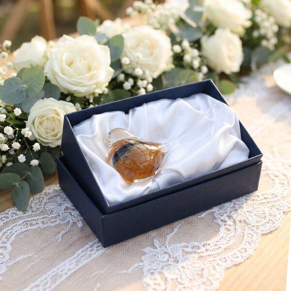 Skleněný ptáček v elegantní dárkové krabičce na svatebním stole s květinovou výzdobou