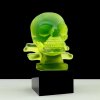 Art Deco skull hood ornament made of uranium glass on black glass base with strong green UV glow