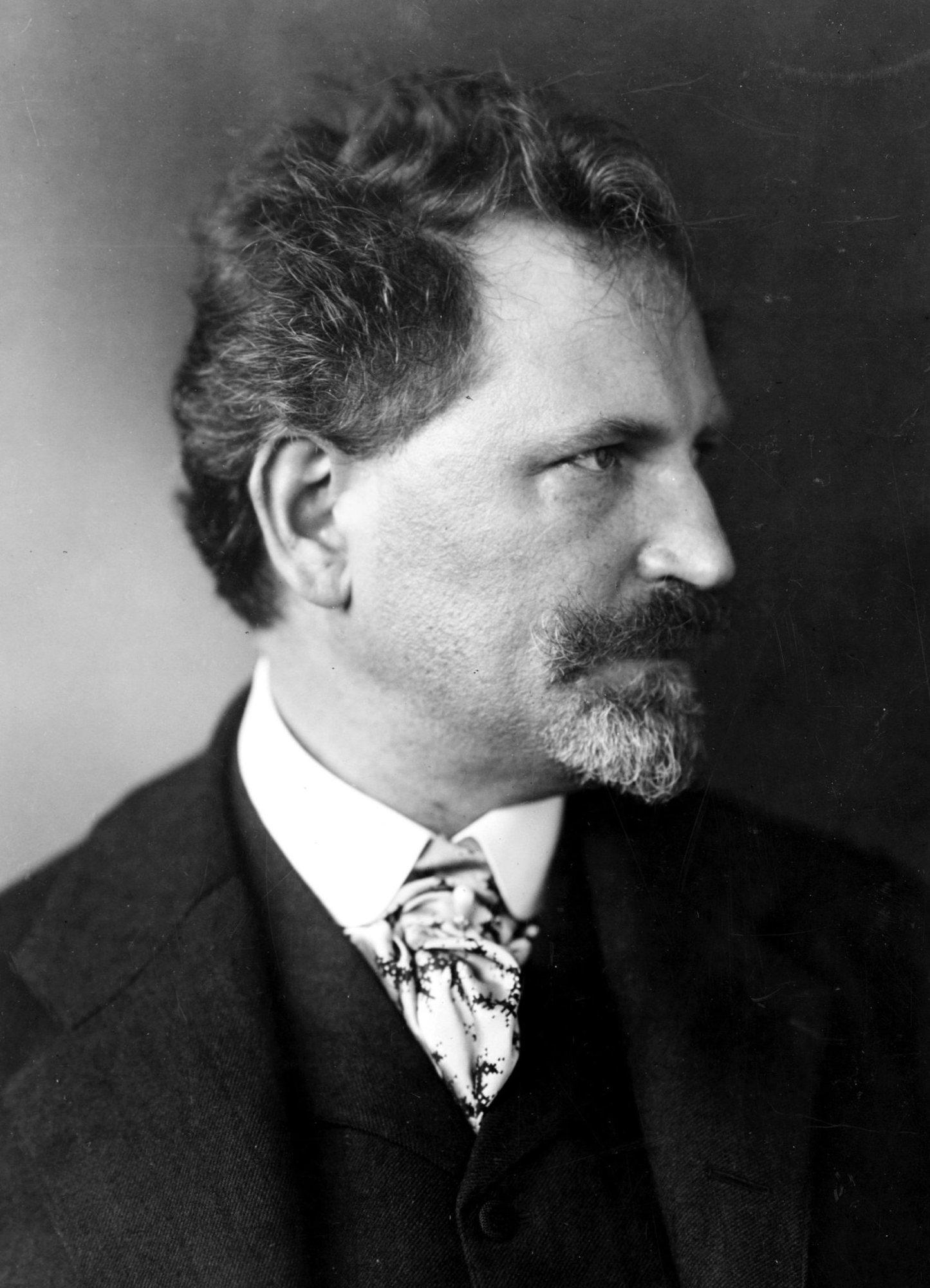 Alfons Mucha kolem roku 1906 – černobílá portrétní fotografie muže s knírem a bradkou v tmavém obleku