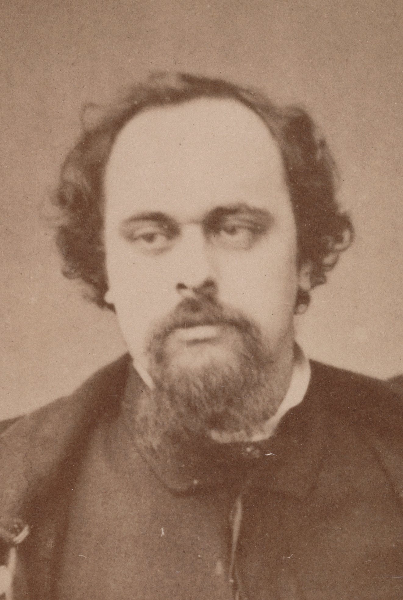 Fotografie Danteho Gabriela Rossettiho z prosince 1862 – muž s plnovousem a tmavými vlasy v tmavém kabátě