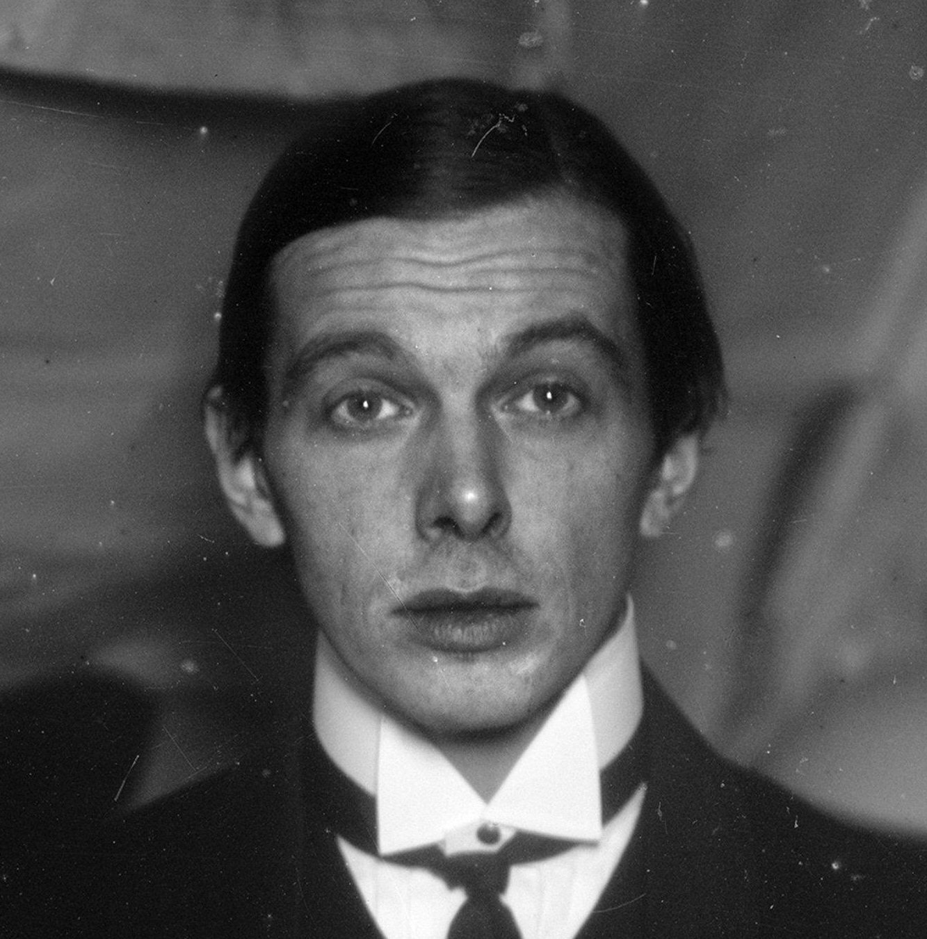 Ernst Ludwig Kirchner na vlastní fotografii z ateliéru v Berlíně-Friedenau, kolem 1913–1915 – mladý muž v bílé košili a tmavém saku hledí do objektivu