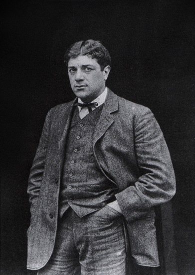 Georges Braque v roce 1908 – černobílá fotografie mladého muže v tvídovém obleku s motýlkem a rukama v kapsách
