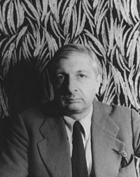 Giorgio de Chirico v roce 1936 – černobílá portrétní fotografie muže v saku a kravatě před látkou se vzorem listů