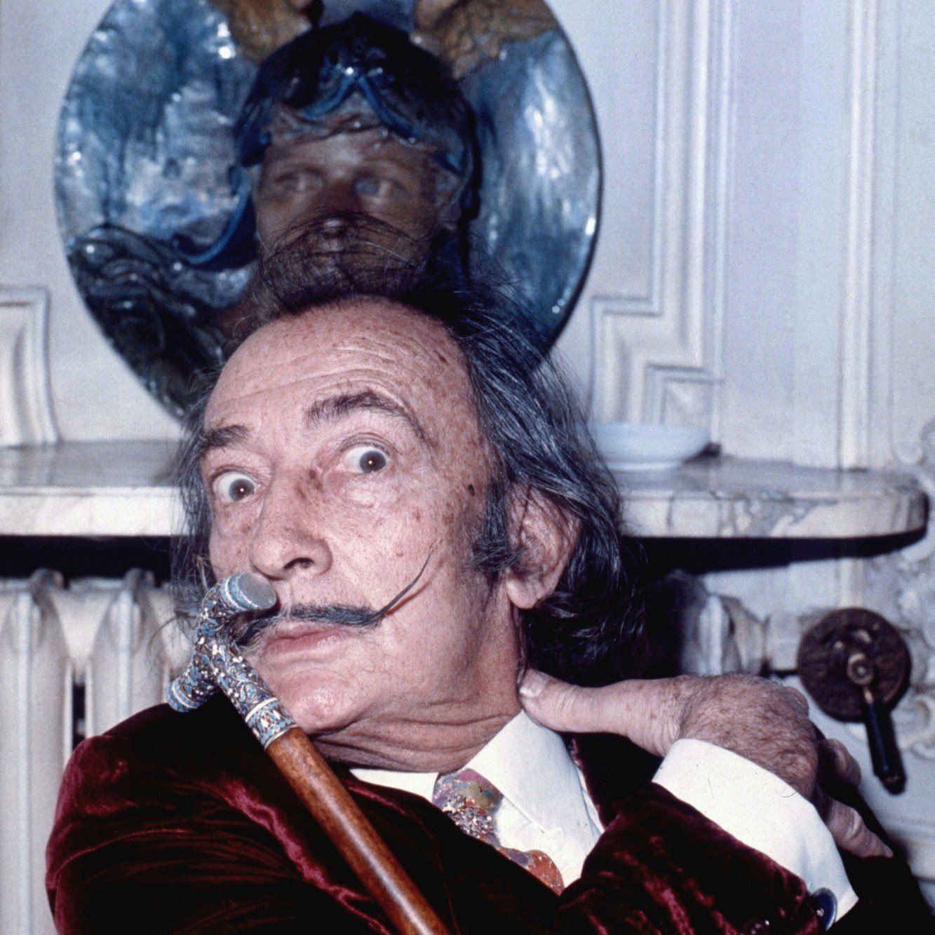 Salvador Dalí v roce 1972 v pařížském hotelu Meurice – starší muž s dlouhými vlasy, vytočeným knírem a vycházkovou holí