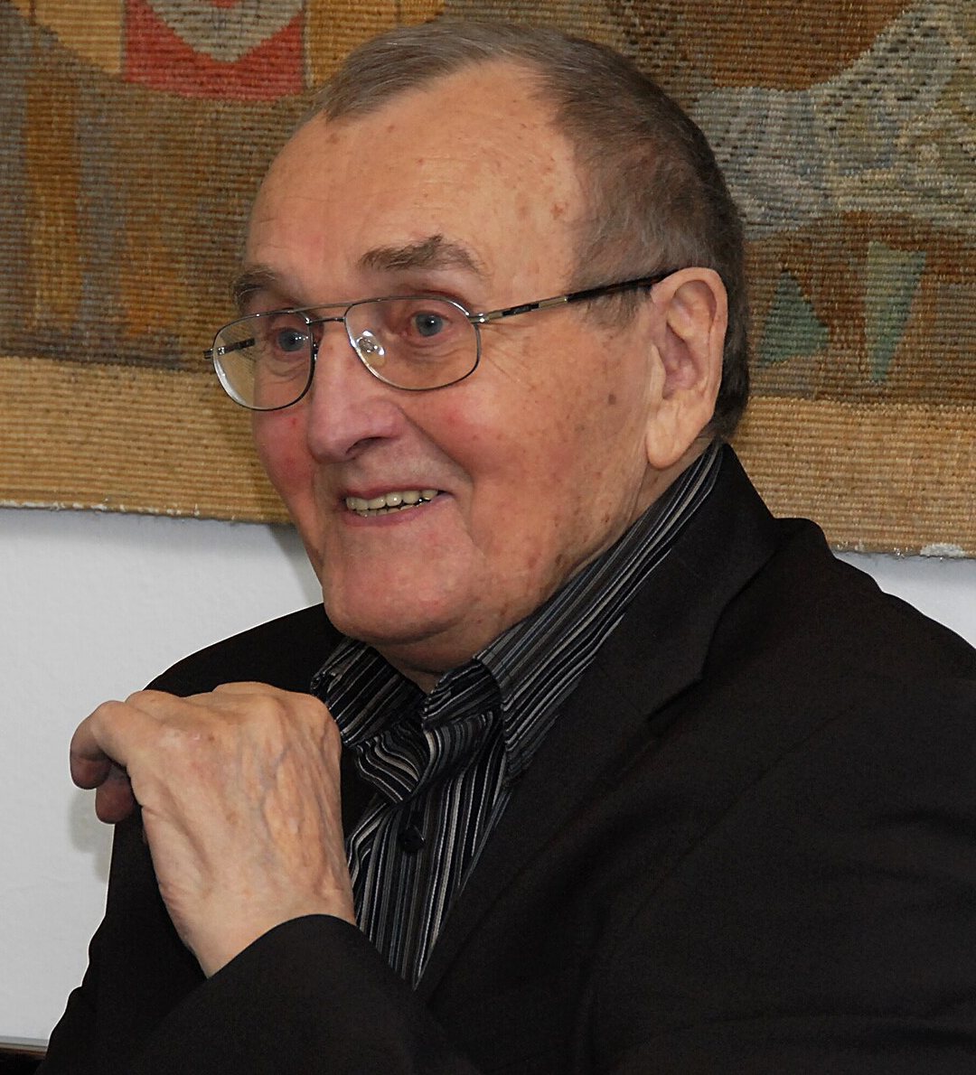 Zdeněk Sýkora v roce 2010 – starší muž v brýlích a tmavém saku s pruhovanou košilí, usmívá se