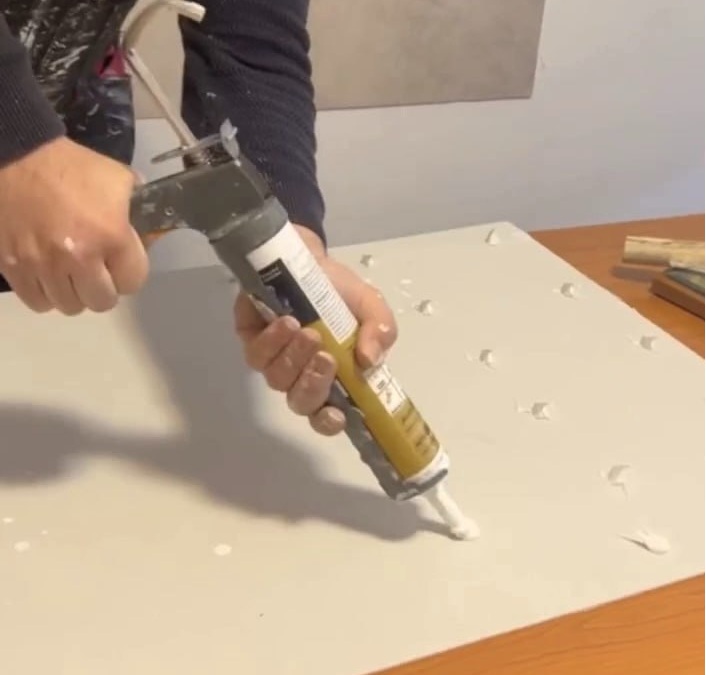 Applying adhesive on PVC wall panel before installation close up