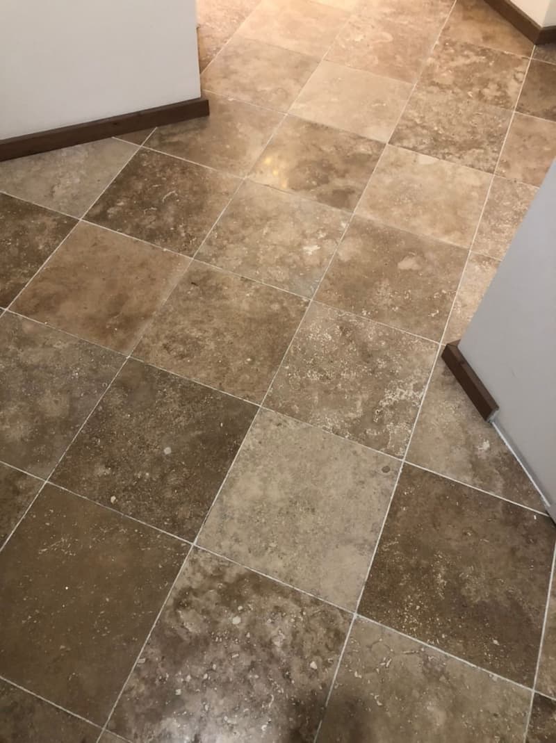 Travertine floor tiles installed in interior space showing natural color variation