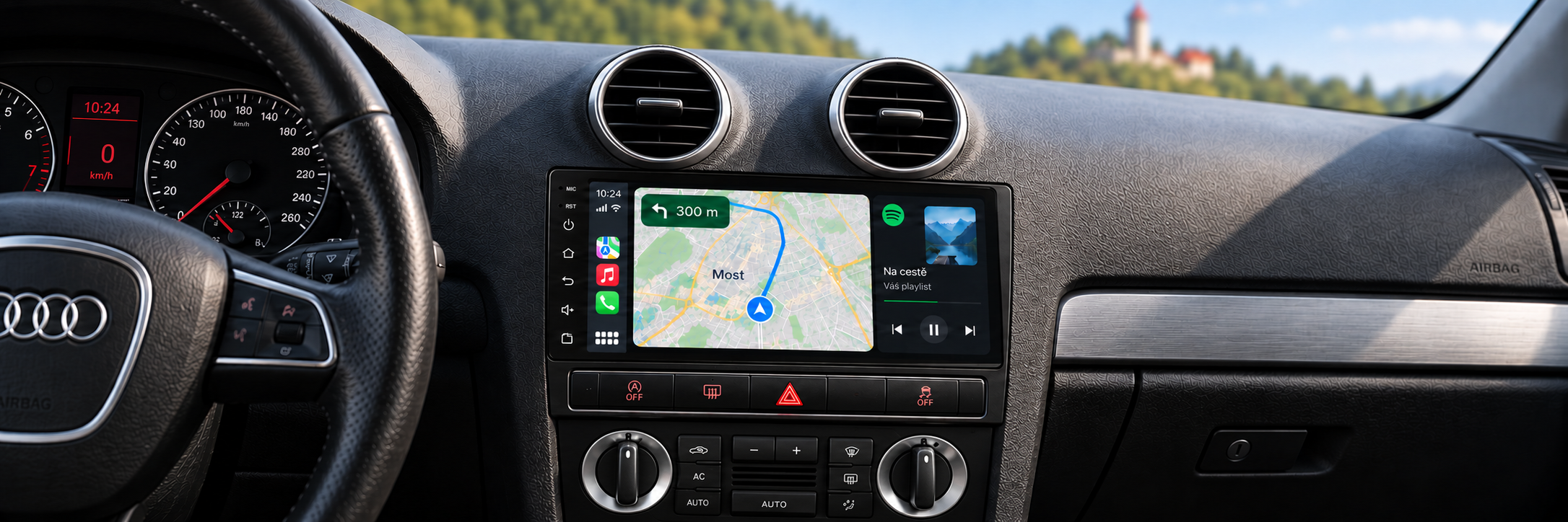 CarPlay s navigací Most v interiéru Audi A3 a rozmazaným Hněvínem v pozadí