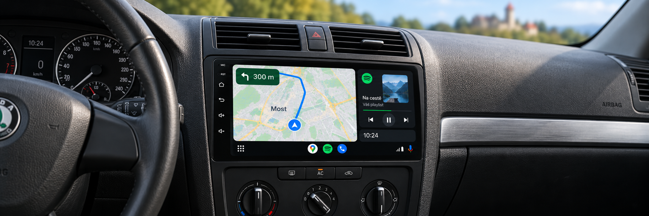 Android Auto s navigací Most a rozmazaným hradem Hněvín v pozadí – ilustrační zobrazení