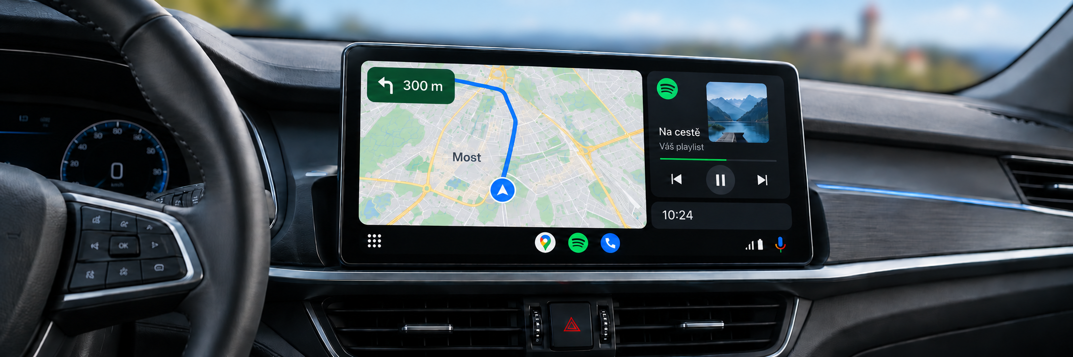 Android Auto s navigací Most a rozmazaným hradem Hněvín v pozadí – ilustrační zobrazení