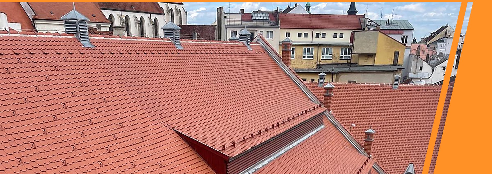 Pálená bobrovka s vikýři nad střechami města – vyberte doplňky ke své krytině