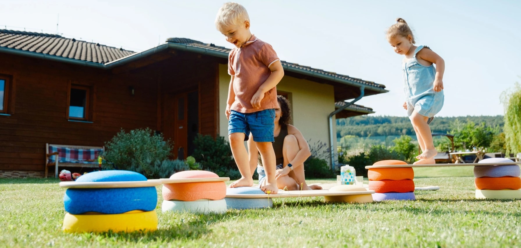 Letní piknik a děti hrající si s balančními mostky a kameny Stapelstein