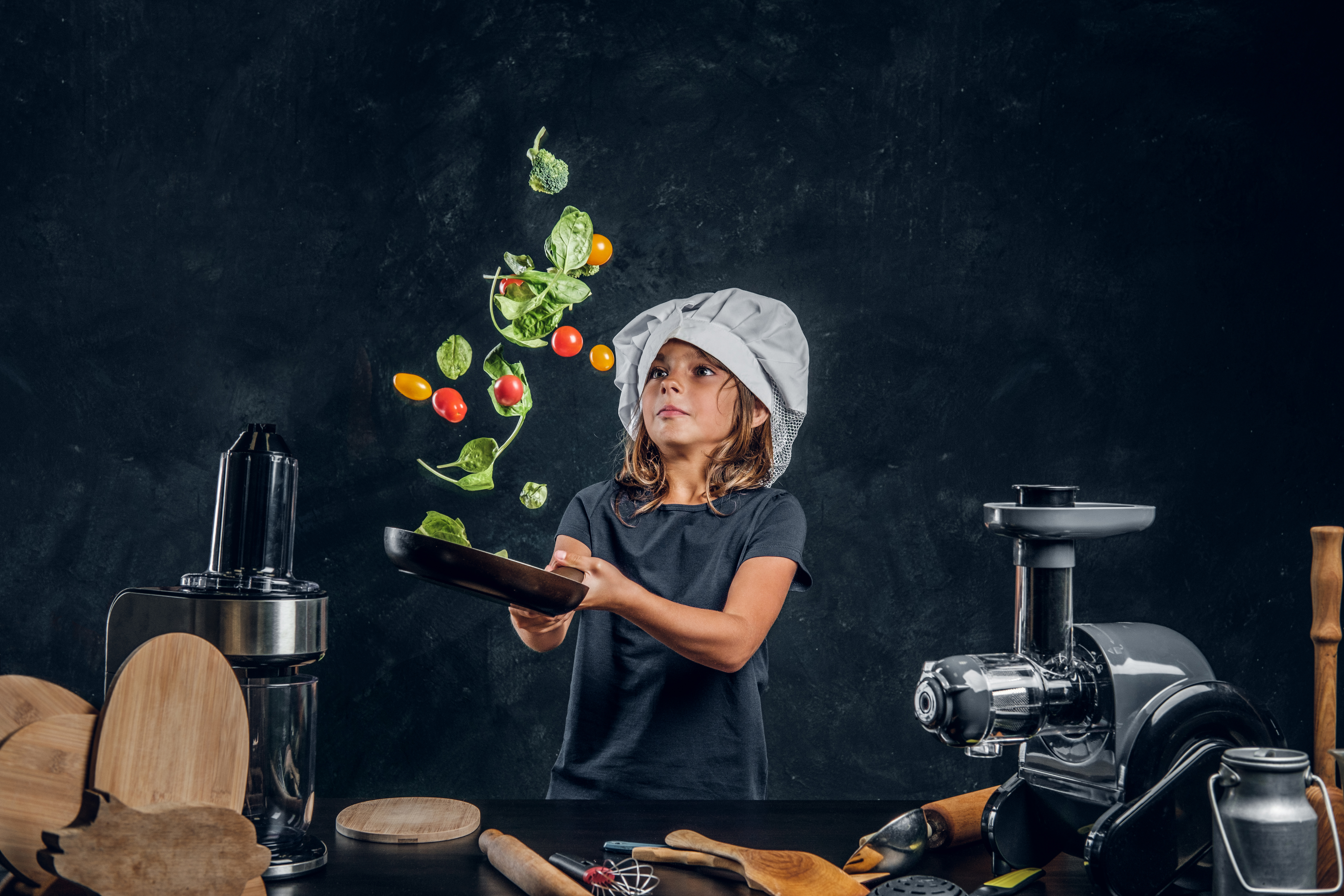 pretty-little-girl-is-tossing-vegetables-pan-dark-photo-studio