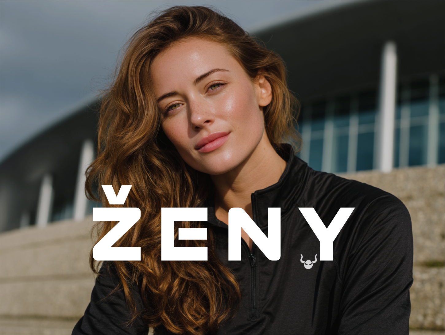 Športovo oblečená žena v čiernej funkčnej mikine Beasthy, pred modernou budovou, reprezentuje kolekciu dámskeho športového oblečenia – legíny, podprsenky, mikiny a topy pre ženy, fitness móda pre ženy, oblečenie na cvičenie, beh, jogu a silový tréning.