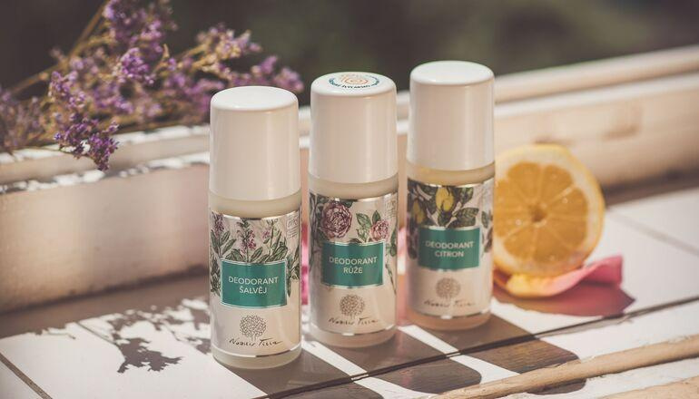Tři přírodní deodoranty Nobilis Tilia – Růže, Šalvěj a Citron, na slunci s květy levandule a plátkem citronu.
