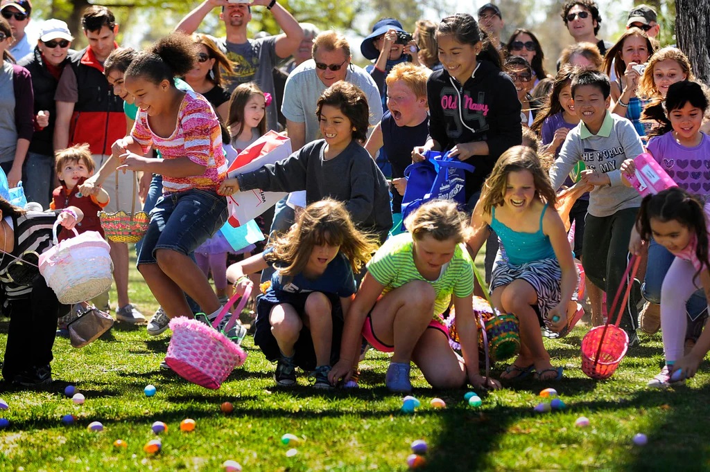 Děti při hledání velikonočních vajíček Easter egg hunt v USA v parku plném barevných vajíček