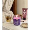 Zapálená sviečka DW Home Lavender & Chamomile na nočnom stolíku s čajom a kozmetikou