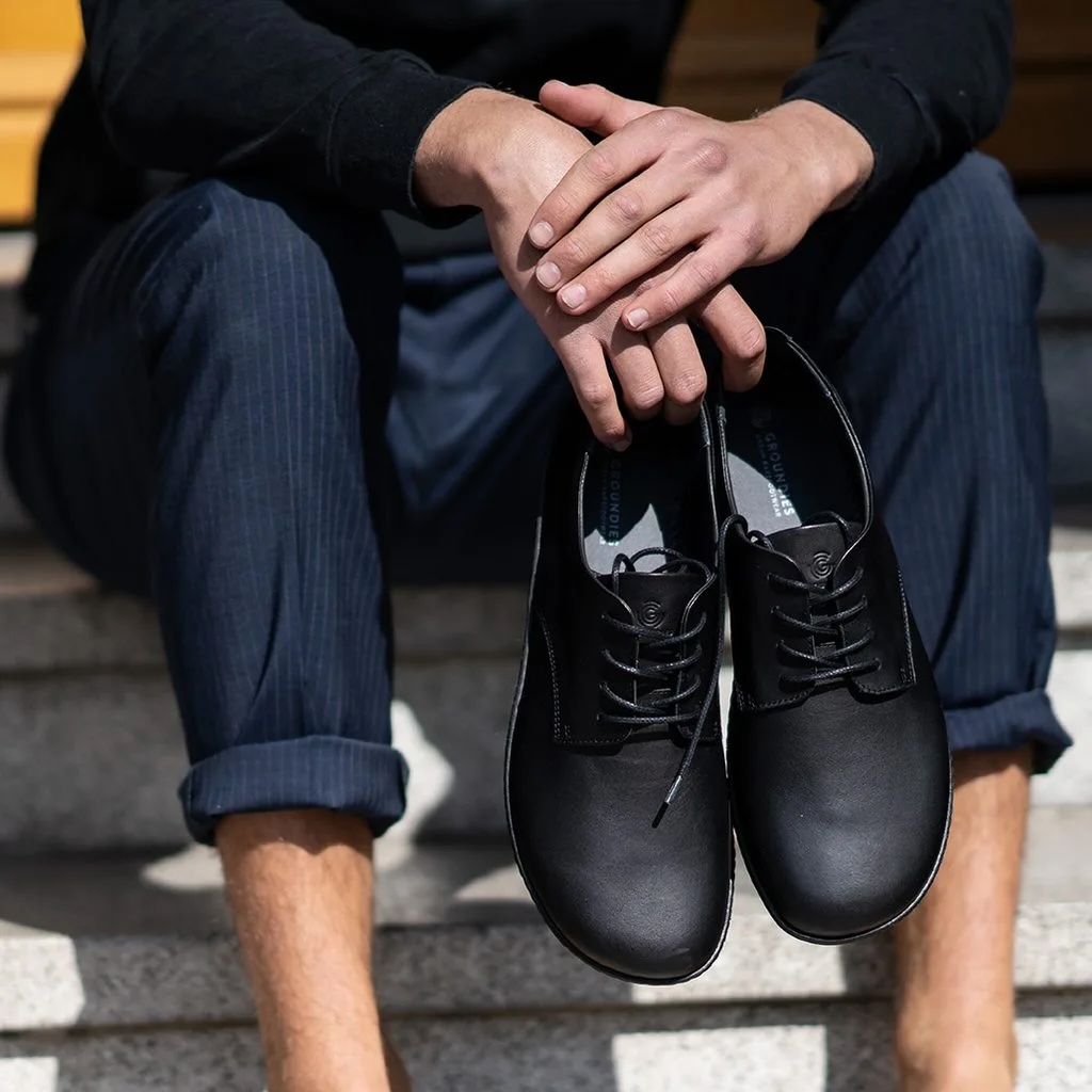 Person holding a pair of black barefoot shoes