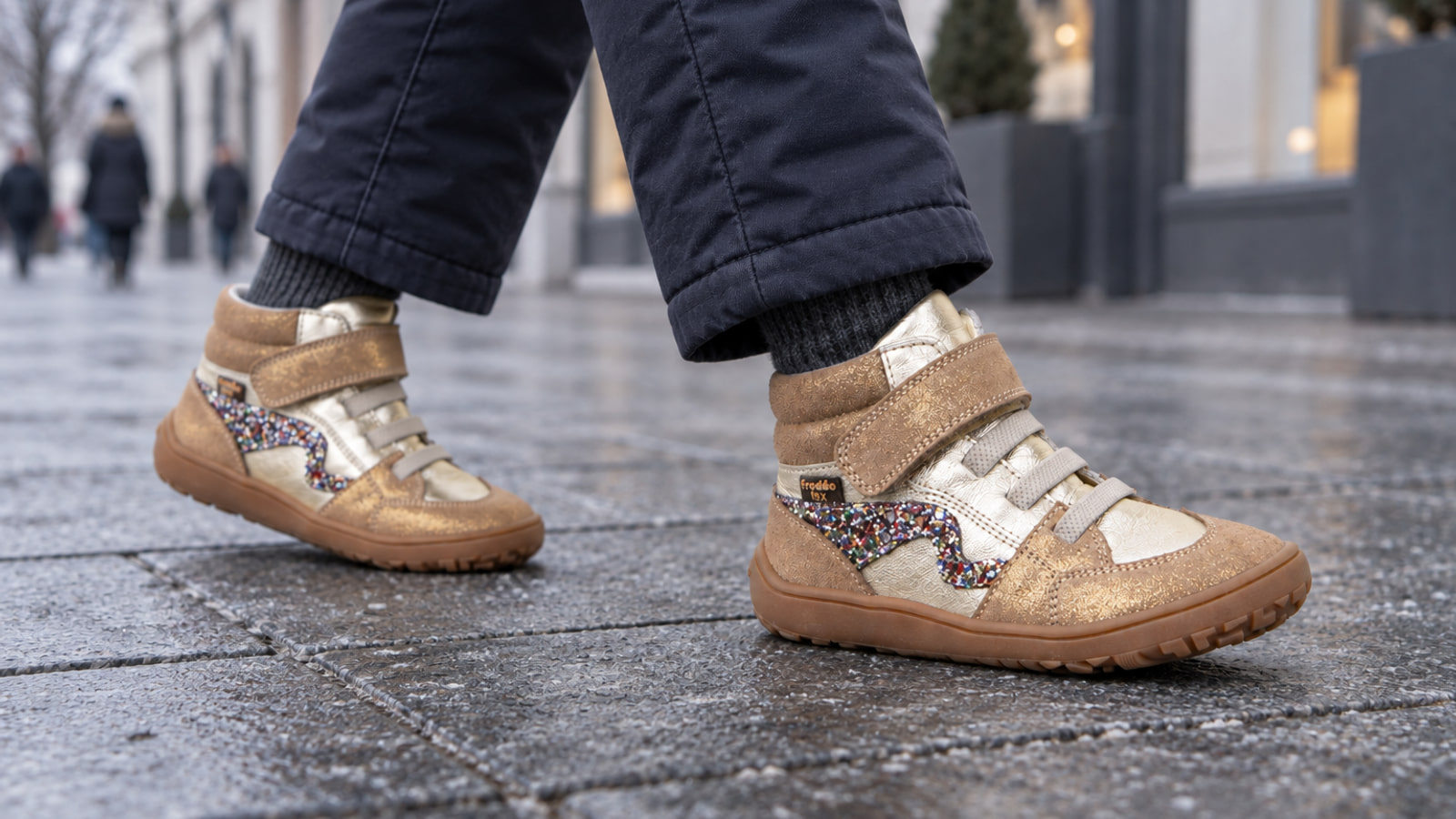 Child wearing lightly insulated gold Froddo barefoot shoes in a winter city
