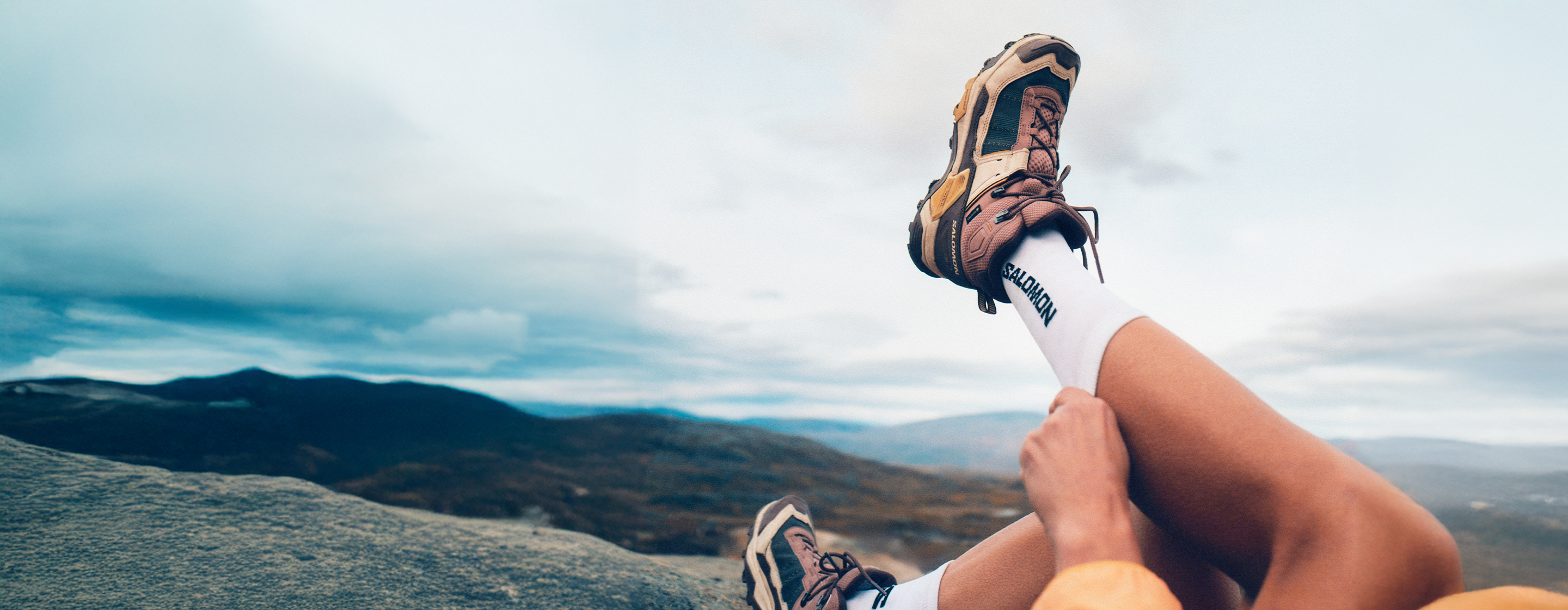 žena-ležící-v-trávě-v-botech-salomon-během-turistiky