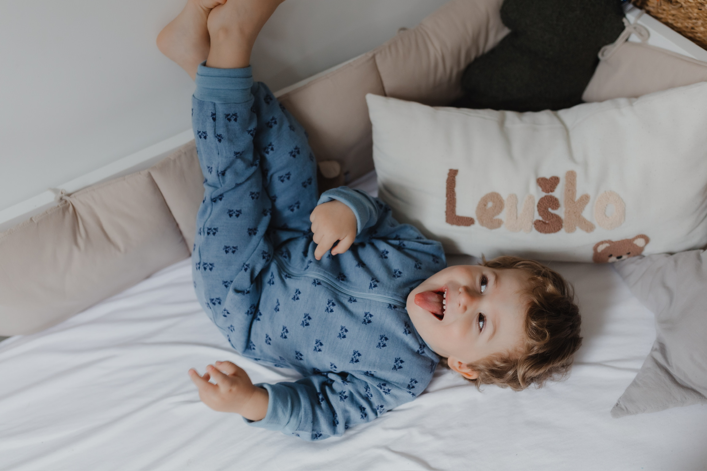 Kind schläft ruhig im Bett, trägt geschichtete Kleidung passend zur Jahreszeit