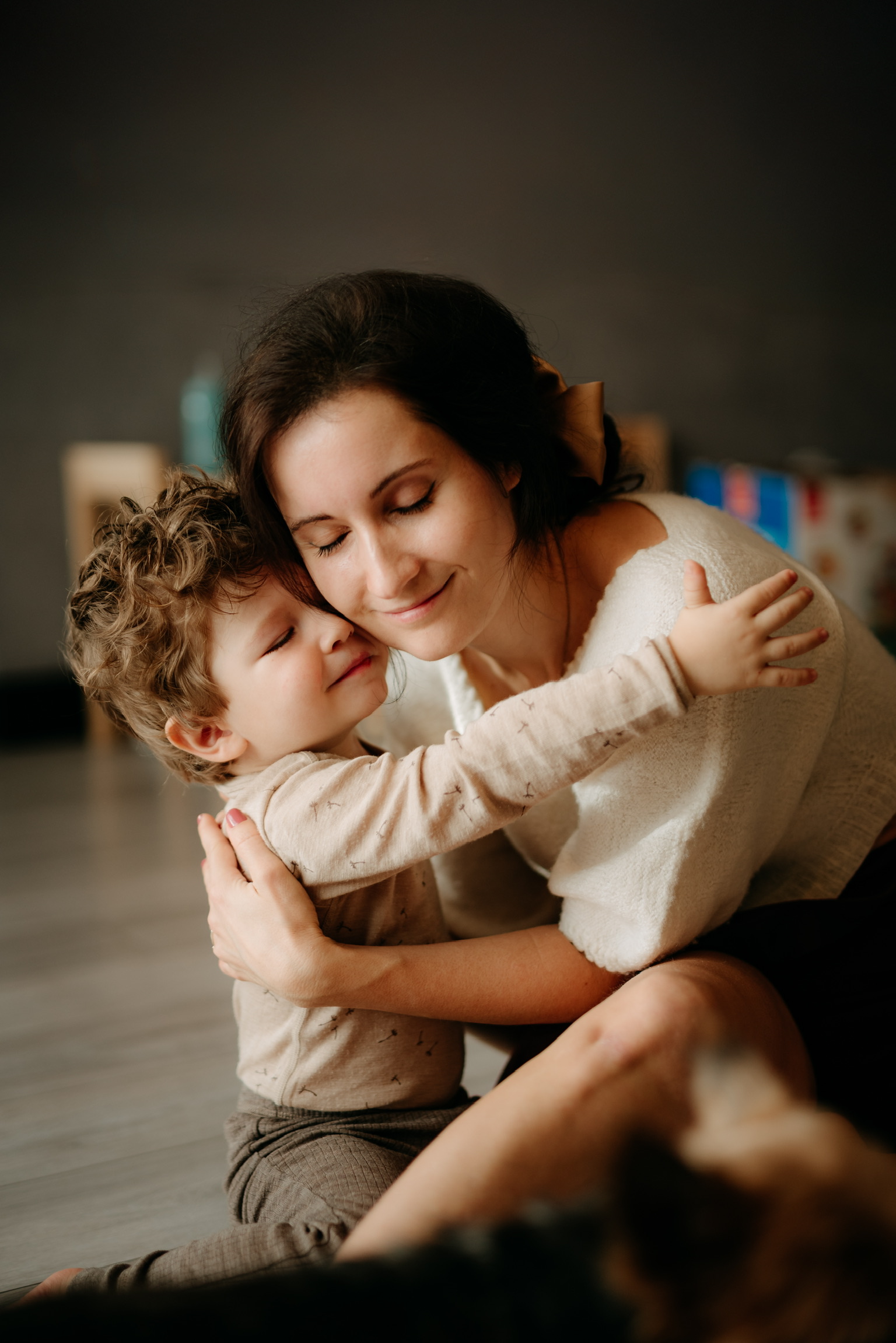 Mutter umarmt zufriedenes Kind beim Familienfotoshooting