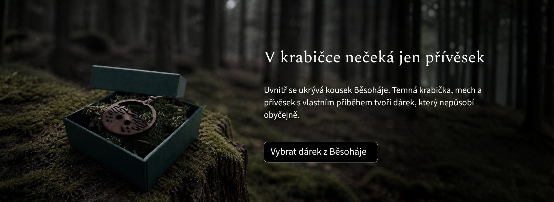 Dřevěný přívěsek Běsoháj v tmavé dárkové krabičce s lesním mechem, položený na pařezu v tlumeném lese.