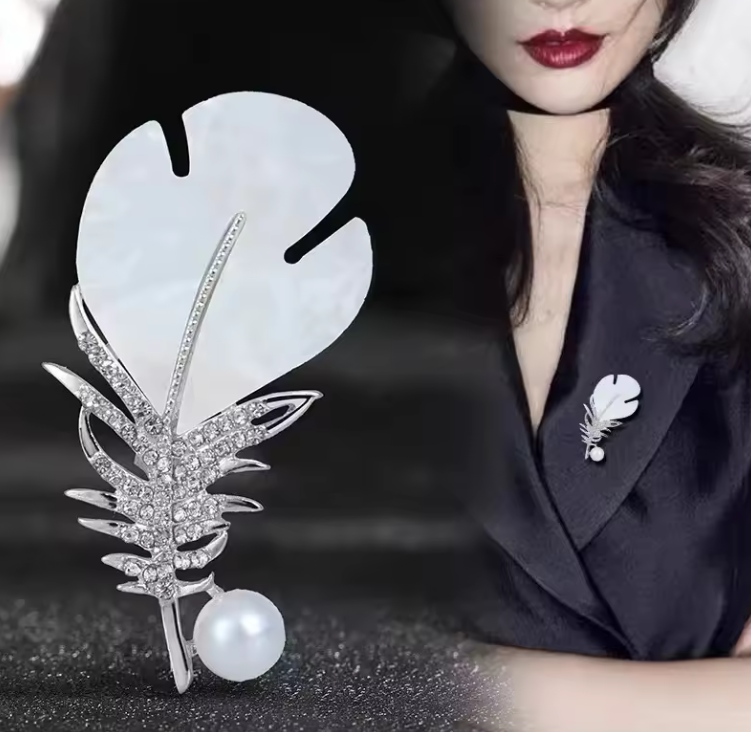 Pozlátená brošňa v tvare pierka s kryštálmi