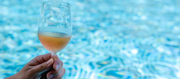 hand-toasting-with-glasses-rose-wine-swimming-pool_74663-115