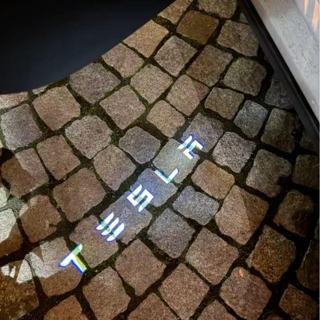 Projekce nápisu Tesla na dlažbě